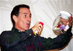Trevor Romain, a noted children's author, demonstrates the power of using storytelling and visual aids to reach military children during the Defense Department's Joint Family Readiness Conference in Chicago, Sept. 2, 2009. As an example, he held up a toy mouse inside a glass bowl. Just as nothing he sprays on the bowl reaches the mouse, he said, children can �shield� themselves from mean remarks. DoD photo by Elaine Wilson  
